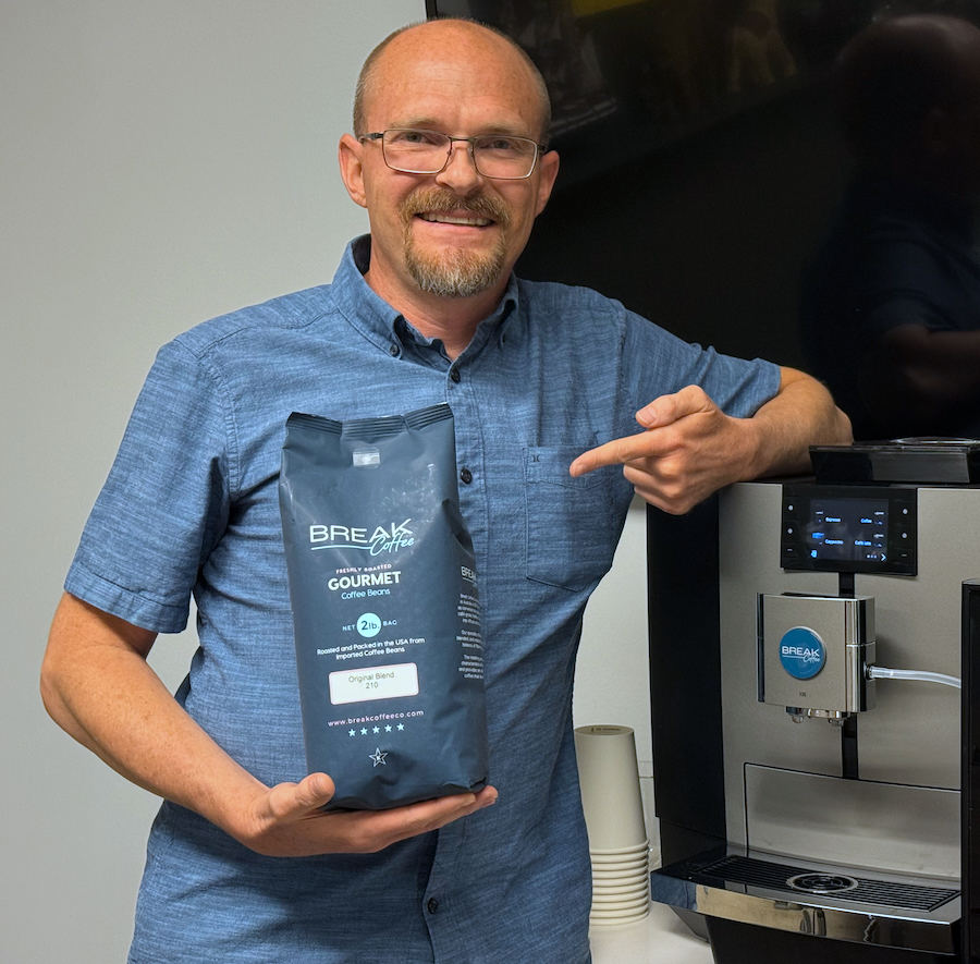 Richard Jones, owner of Break Coffee Co. of Boulder Denver Metro, standing with a machine and beans.